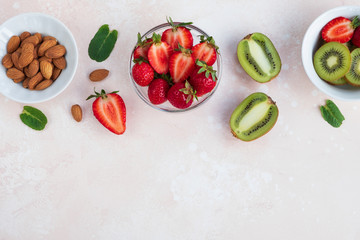 Healthy food, summer diet. Fresh strawberries, kiwi, nuts and mint leaves on light background. Top view, flat lay, copy space
