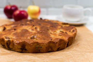 Homemade baked apple pie, in a plate, on a white wooden table, ready to eat. Place for an inscription...