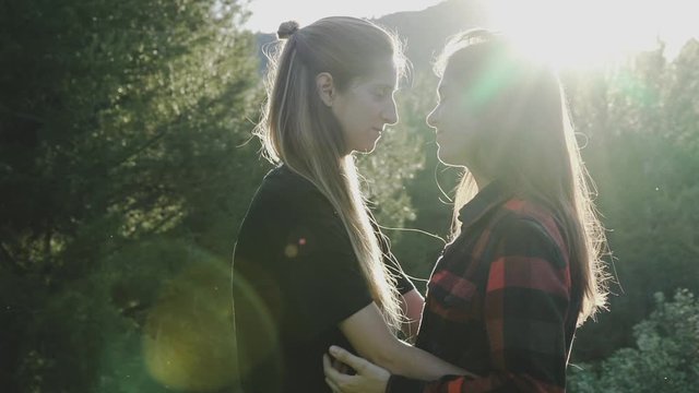 Lesbian girls couple hugging and kissing under the sunset.