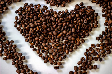 Aromatic coffee beans in the form of heart. Heart from coffee beans isolated on a white background. Coffee beans heart shape. Heart-shaped coffee beans isolated from a beautiful white background.