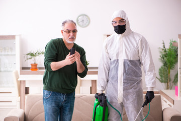 Young male sanitizer and old man indoors