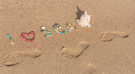 Fototapeta na wymiar Summer concept with sandy beach, shells and colored stones