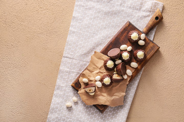 Board with tasty chocolate candies on color background