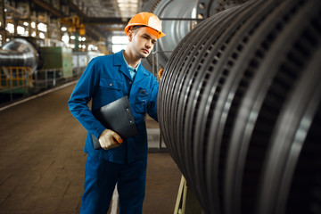 Worker with notebook, large turbine on background