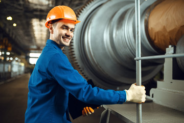 Engineer on factory, large turbine on background