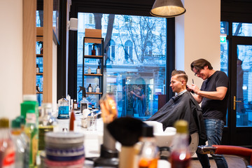 Barber trims the hair of young man with a razor