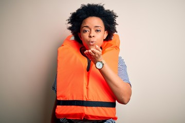 Young African American afro woman with curly hair wearing orange protection lifejacket looking at...