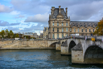 Scenic view of the Seine, Pont Royal and the Louvre Museum in Paris, France, with the dramatic sky. Louvre is one of the most famous art museums in the world