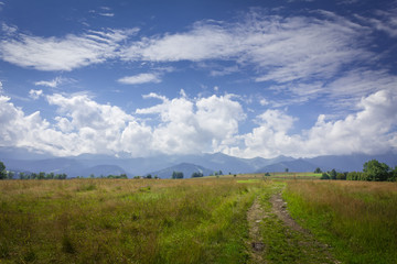 Fototapeta premium Poland. Polish Tatry mountains. View of the cloudy mountains. A dirt road, meadows.