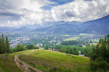 Fototapeta premium Poland. Polish Tatry mountains. View of the cloudy mountains. In the valley the city of Zakopane.