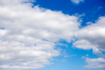 White fluffy clouds in blue sky in summer. Background with cloud