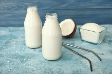 Bottles of tasty coconut milk on color background