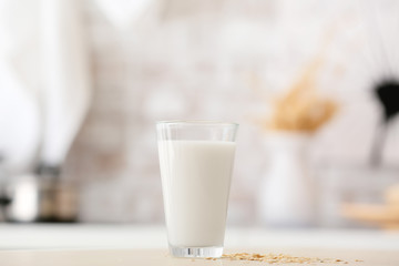 Glass of tasty oat milk on table
