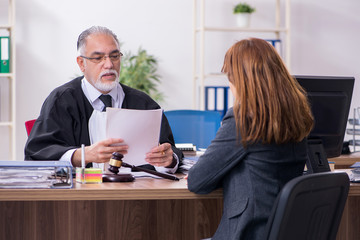 Old male judge and female client in the office