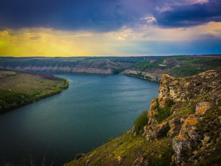 Panoramic view from the hill on bend of the river. Beautiful summer landscape. Colorful clouds of the morning sky. Dniester Canyon located at the territory of Dniester River