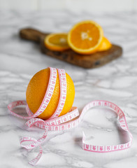 ripe orange wrapped with measuring tape