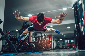 Portrait of a fitness man doing extreme push ups in gym. Selective focus.
