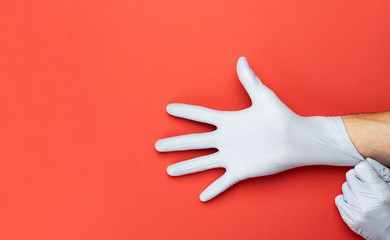 Virus protection. Using medical lab gloves on red background. Risk Coronavirus disease COVID-19 pandemic concept by washing hands frequently. Professional safety and hygiene for surgery.