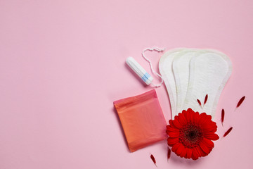 menstrual sanitary cotton pads, tampons and red flower isolated on pink background, copy space, top view.