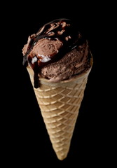 Cones with chocolate ice cream scoop and topping isolated on black background with clipping path
