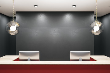 Contemporary red reception table with two computers and blank wall.
