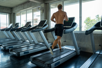 Fototapeta na wymiar Fitness man are running on modern electric treadmills at the gym,Man on electric treadmills.