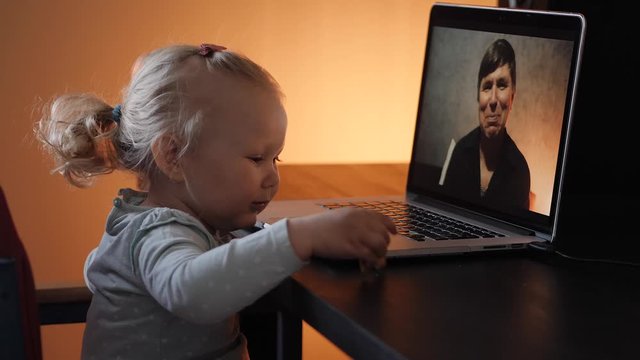 The little girl in the video on the laptop waving to the grandfather online