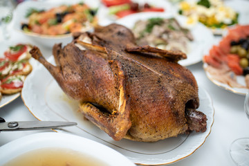 Freshly baked duck on the plate with other dishes on a holiday table