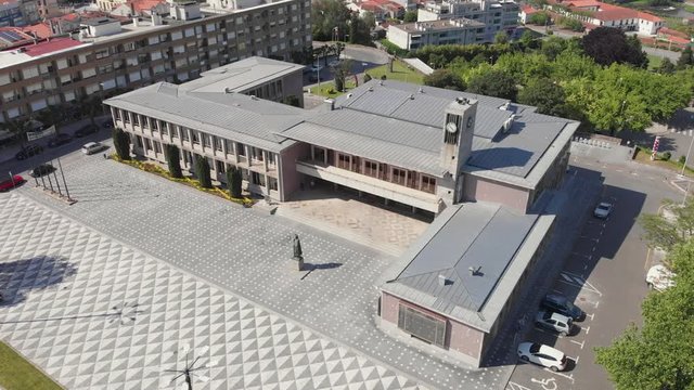 AERIAL DRONE FOOTAGE - Santo Tirso City Hall with the statue of Saint Rudesind (Sao Rosendo) in front. The Monastery of Saint Benedict (Sao Bento) in the background, Santo Tirso, Portugal.