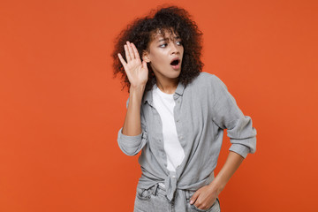 Shocked young african american woman girl in gray casual clothes posing isolated on orange...