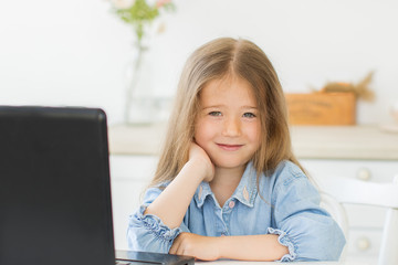 Pretty preschool girl studing at home with digital table laptop.