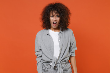 Shocked irritated young african american woman girl in gray casual clothes isolated on orange background studio portrait. People lifestyle concept. Mock up copy space. Keeping mouth open, swearing.