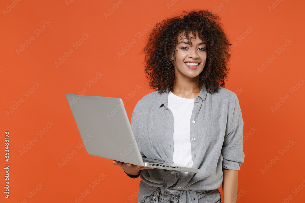 Wall mural smiling young african american woman girl in gray casual clothes isolated on orange wall background 