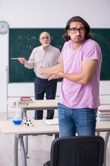 Fototapeta premium Old chemist teacher and two students in the classroom