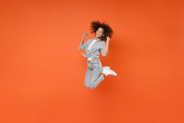 Happy young african american woman girl in gray casual clothes posing isolated on orange wall...