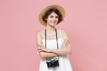 Smiing tourist woman in summer white dress hat with photo camera on neck isolated on pink...