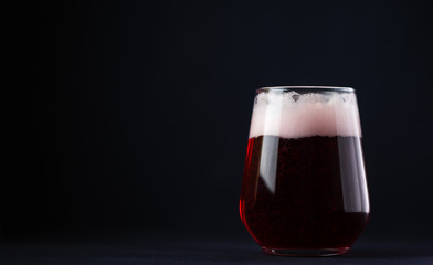 Craft cherry beer on a dark background in a glass with copy space