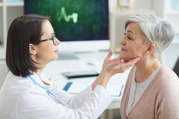 Side view portrait of female doctor examining senior woman during consultation in medical clinic