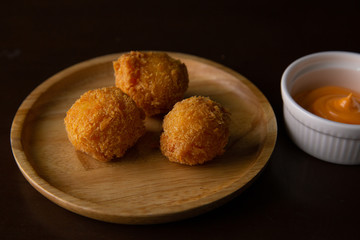 Cheese ball on a wooden plate on a black background