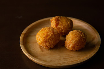 Cheese ball on a wooden plate on a black background