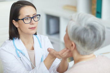 Obraz premium Portrait of young female doctor examining senior woman during consultation in medical clinic