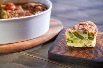 Broccoli egg cheese casserole in baking dish on concrete background