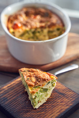Broccoli egg cheese casserole in baking dish on concrete background