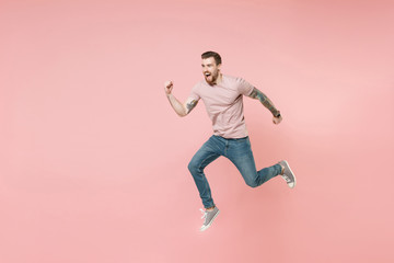 Fototapeta na wymiar Excited young tattooed man guy in pastel casual t-shirt posing isolated on pink wall background studio portrait. People sincere emotions lifestyle concept. Mock up copy space. Jumping like running.