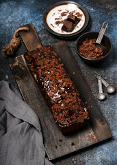 Delicious homemade chocolate cake with chips topping and glaze on rustic wooden cutting bread. Selective focus.