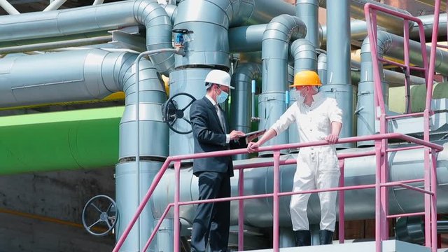 Installation Of Pumping Equipment At A Processing Plant. A Manager With A Laptop Indicates Troubleshooting Equipment. Respiratory Protection At Work.