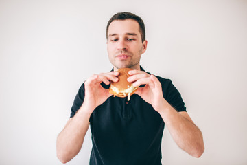 Young man isolated over white background. Guy hold tasty delicious burger in hands and ready to eat it. Looking at meal. Fast food and unhealthy meal.