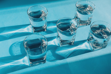 Transparent glasses of pure water on light blue surface. Health care concept