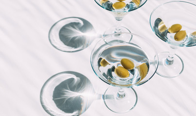 Fresh home made vodka martini in cocktails glasses with olives in white background. Party time