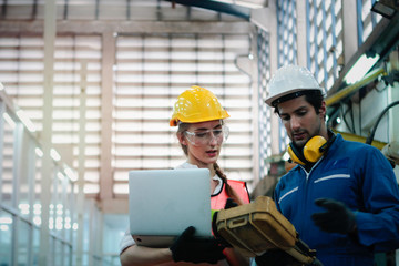 Industrial engineer worker woman and man wearing helmet discussing and working together with robot arm for arduino mechanism at manufacturing plant factory, young people working in industry